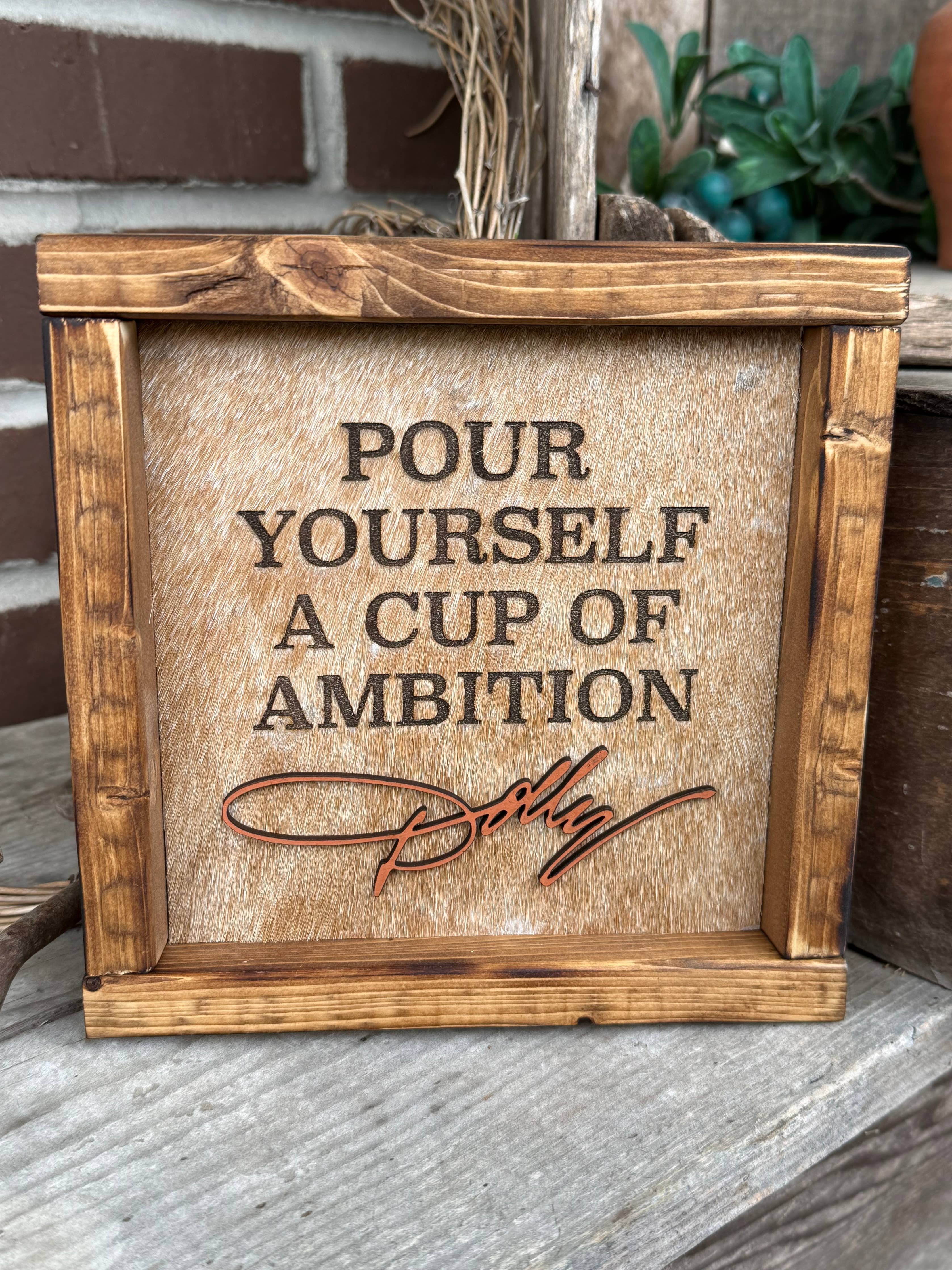 DOLLY PARTON FRAMED COWHIDE SIGN - POUR YOURSELF A CUP OF AMBITION!